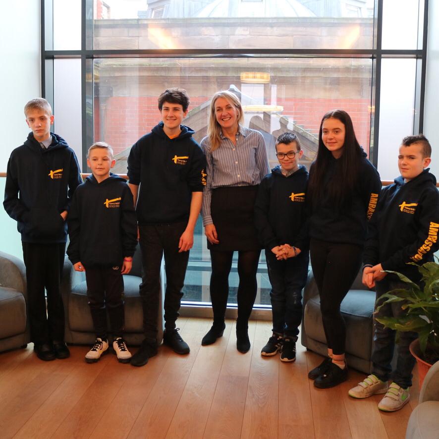Young Ambassadors in Tom's Trust hoodies smiling with Co-Founder Debs