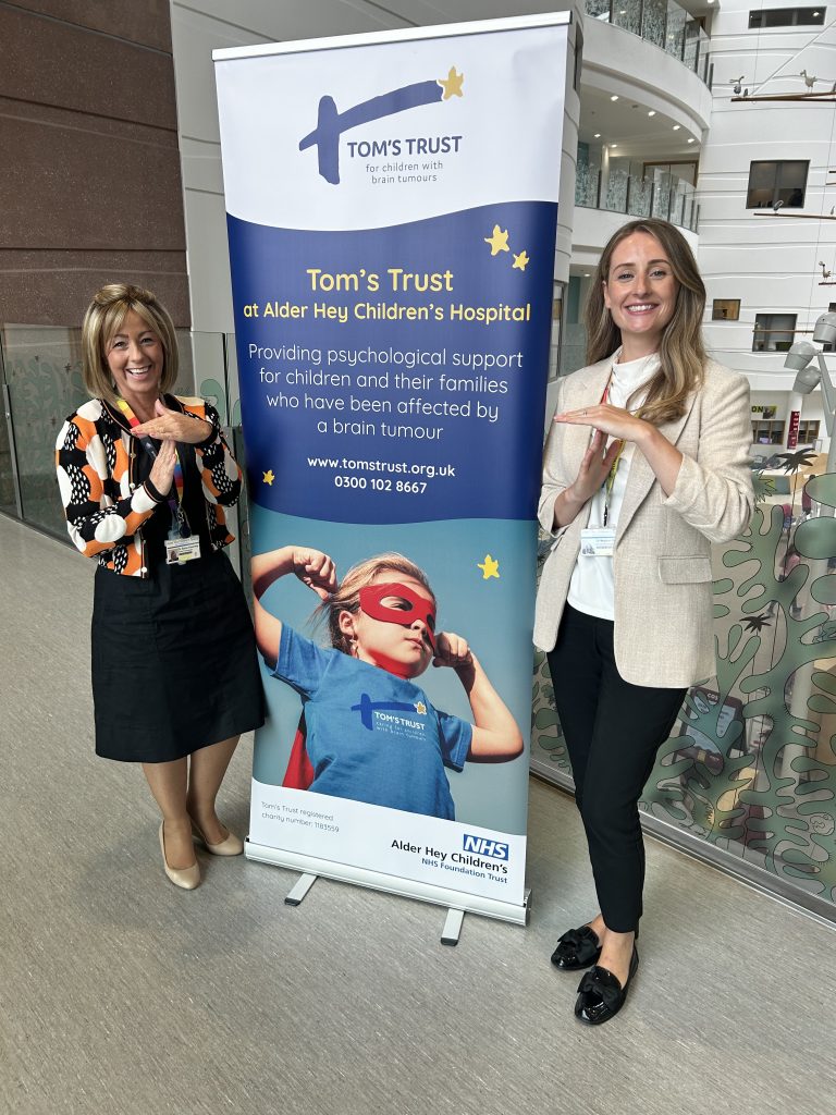 The two psychologists standing in front of a Tom's Trust stand