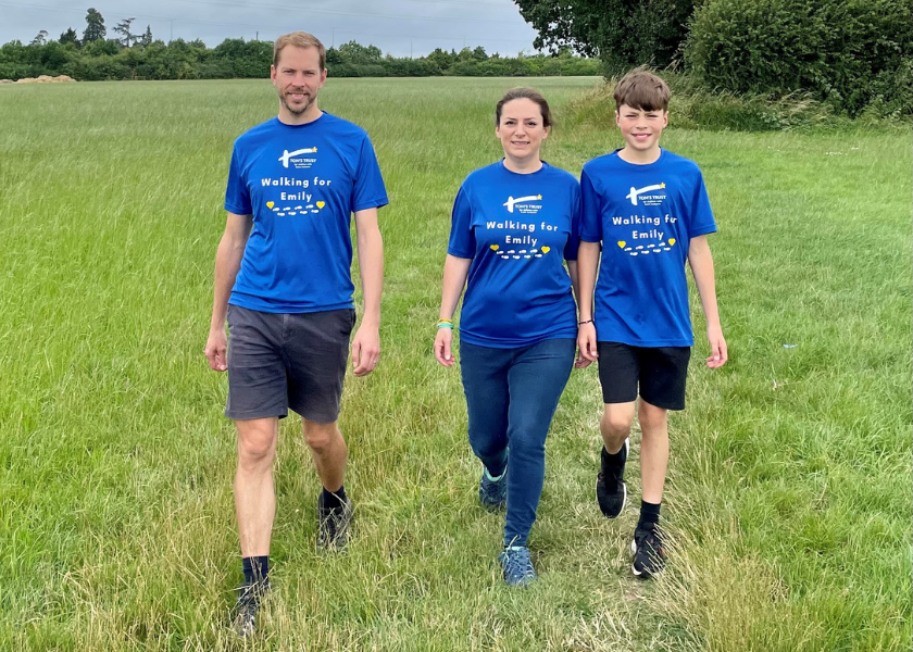 The Smith family walking in a grassy area with Tom's Trust Tshirts on.