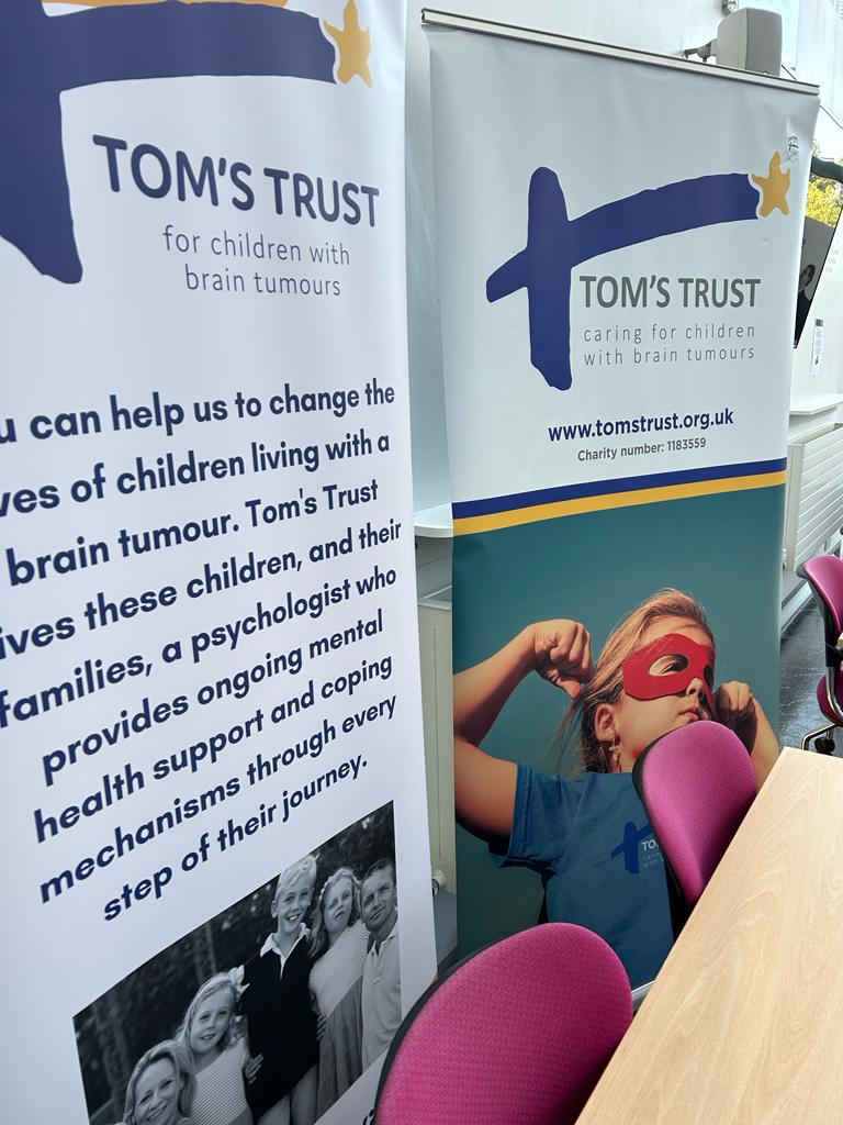 Tom's Trust roller banners placed behind a table with chairs