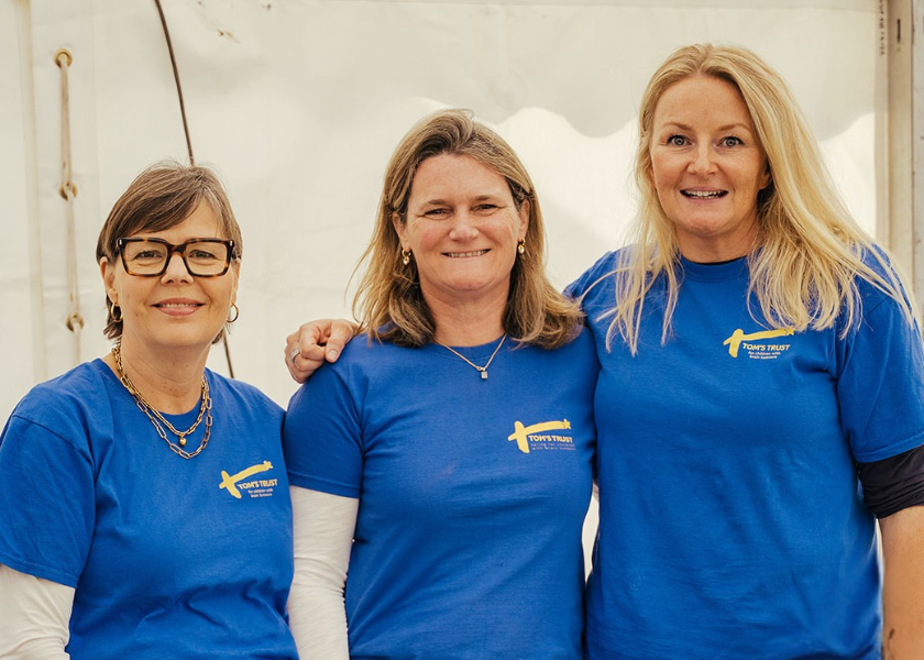 A group photo of Tom's Trust volunteers in blue T-shirts.